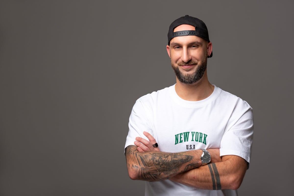 Giacomo Sgolik - Webdesigner mit schwarzer Cap und wei\u00dfem T-Shirt, l\u00e4chelt in die Kamera